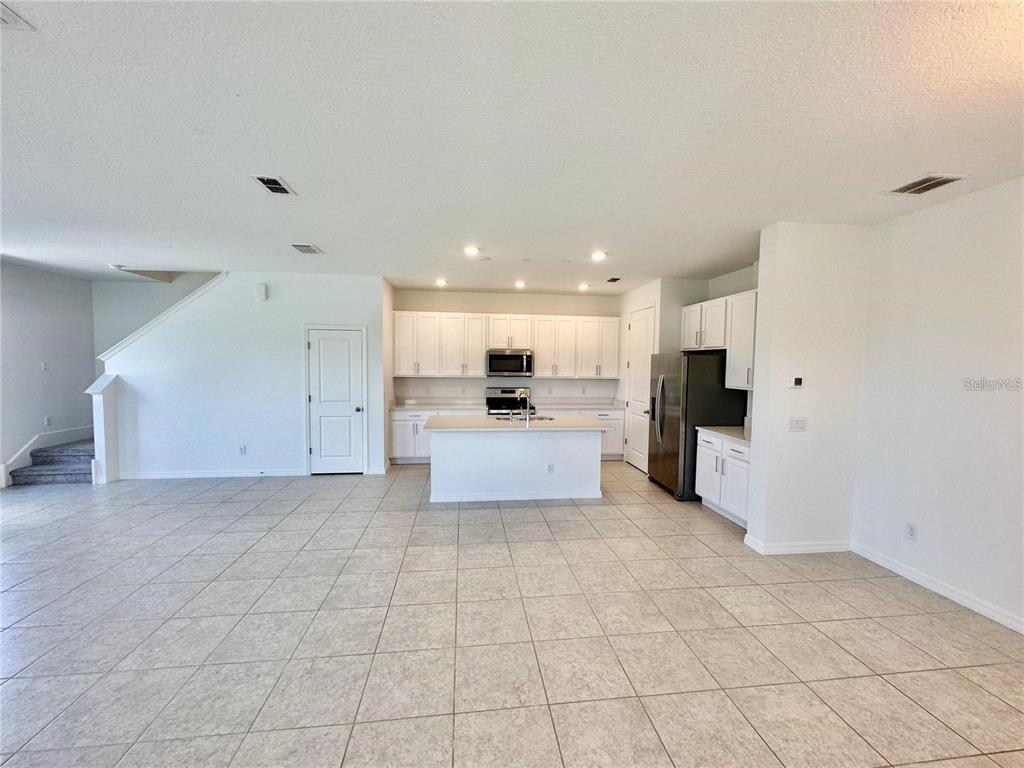 An open-concept kitchen features white cabinetry, a central island, and tile flooring — 1707 SANIBEL DRIVE, DAVENPORT, FL