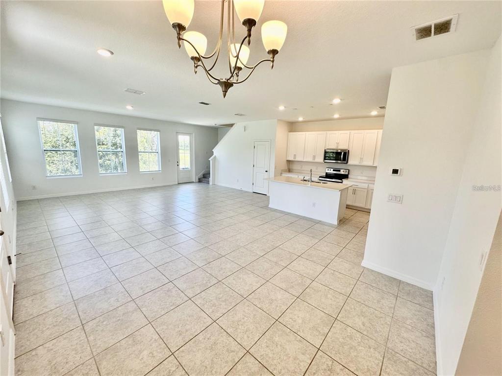 An open-concept kitchen and living area features white cabinetry, tile flooring, and a central island — 1707 SANIBEL DRIVE, DAVENPORT, FL