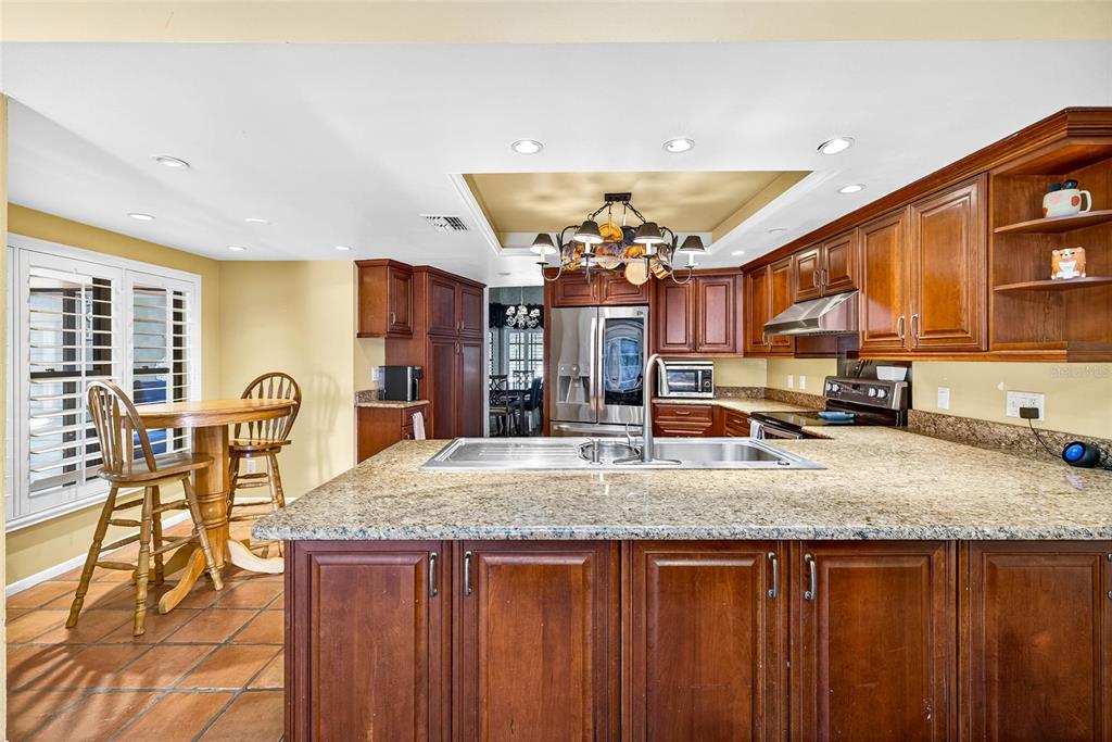A kitchen features wood cabinets, granite countertops, a central island, and a dining nook — 2835 HAMMOCK DRIVE, PLANT CITY, FL