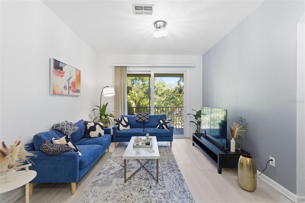 A living room features two blue sofas, a marble coffee table, and a sliding glass door — 1224 S HIAWASSEE ROAD UNIT 630, ORLANDO, FL
