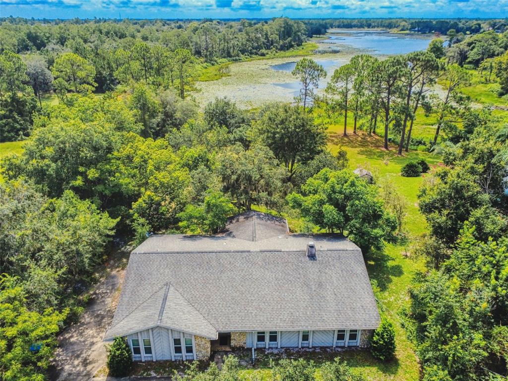 An aerial view of a house with a gray shingled roof near a lake — 799 E LEHIGH DRIVE, DELTONA, FL