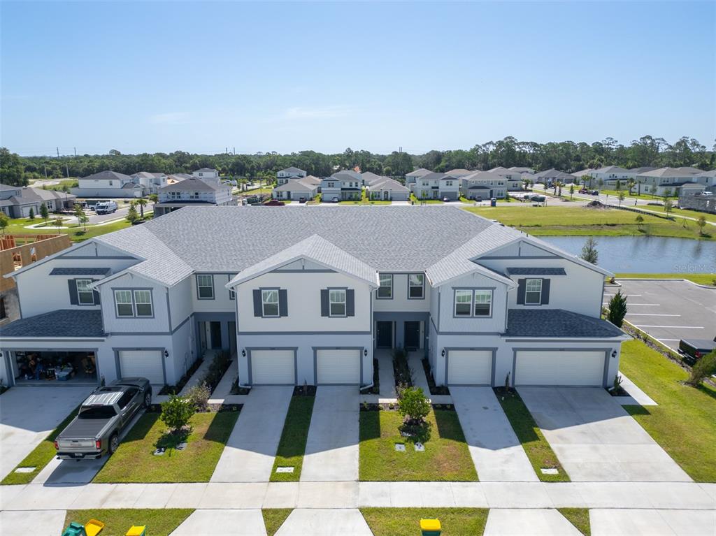 An aerial view of a multi-unit townhouse building with attached garages and a nearby pond — 5055 SUNRISE ESTATES DRIVE, MELBOURNE, FL