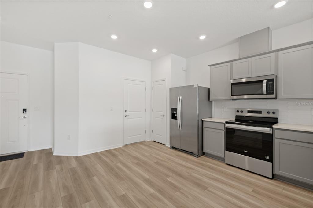 A kitchen features gray cabinets, stainless steel appliances, and light wood-look flooring — 5055 SUNRISE ESTATES DRIVE, MELBOURNE, FL