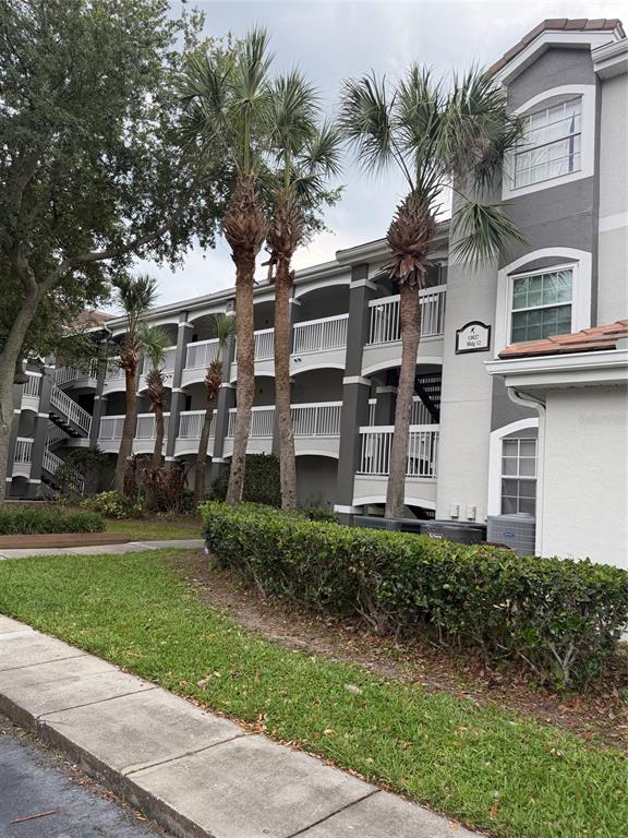 A multi-story apartment building exterior with palm trees, white railings, and a gray facade — 13827 FAIRWAY ISLAND DRIVE UNIT 1228, ORLANDO, FL