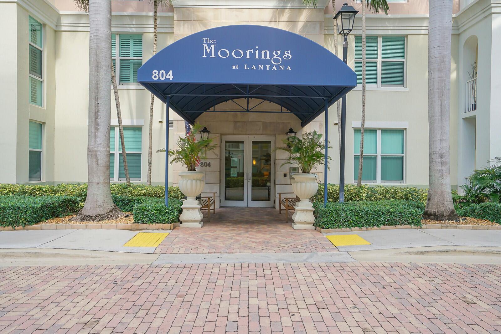 The exterior entrance of a building features a blue awning over glass double doors — 804 E Windward Way, Lantana FL 33462, LANTANA, FL