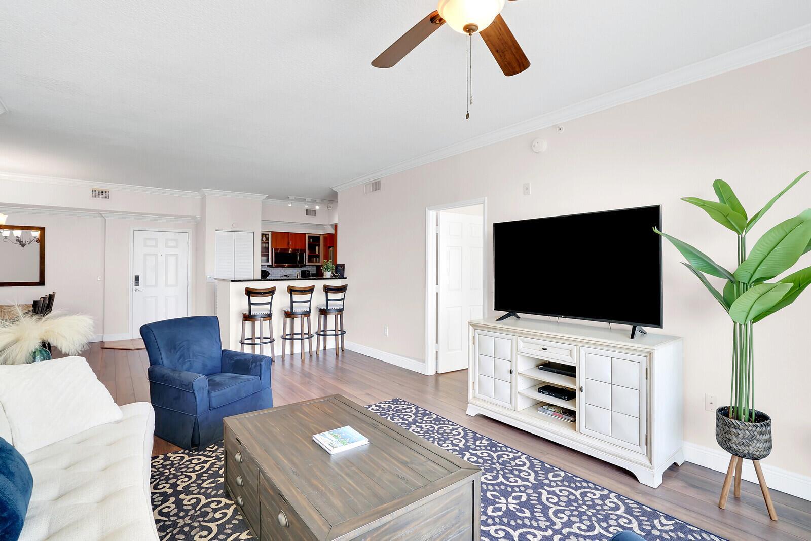 A living room features a blue armchair, a white media console, and a patterned rug — 804 E Windward Way, Lantana FL 33462, LANTANA, FL