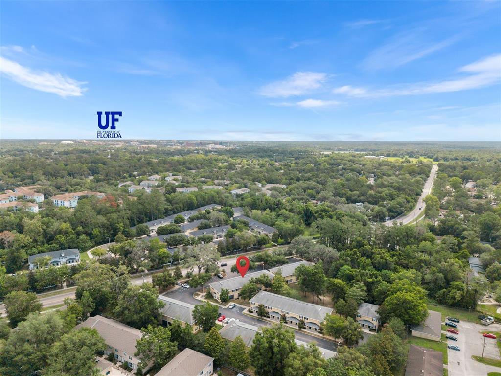 An aerial view shows a multi-unit residential complex surrounded by dense trees and greenery — 2927 SW 35TH PLACE UNIT 113, GAINESVILLE, FL