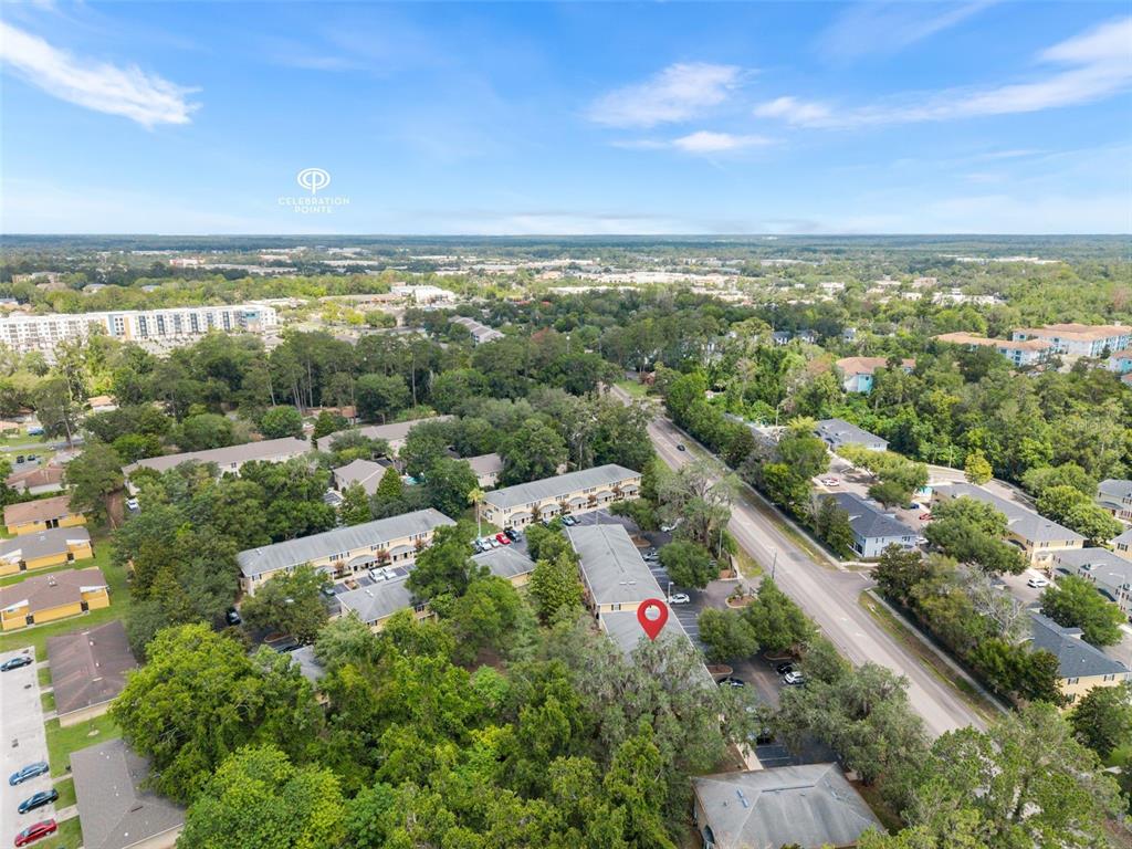 An aerial view shows apartment buildings surrounded by trees and a nearby road — 2927 SW 35TH PLACE UNIT 113, GAINESVILLE, FL