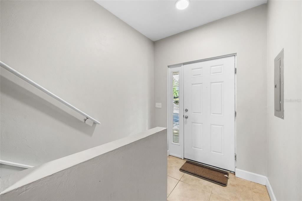 An entryway features a white front door, a staircase with a railing, and tile flooring — 2927 SW 35TH PLACE UNIT 113, GAINESVILLE, FL