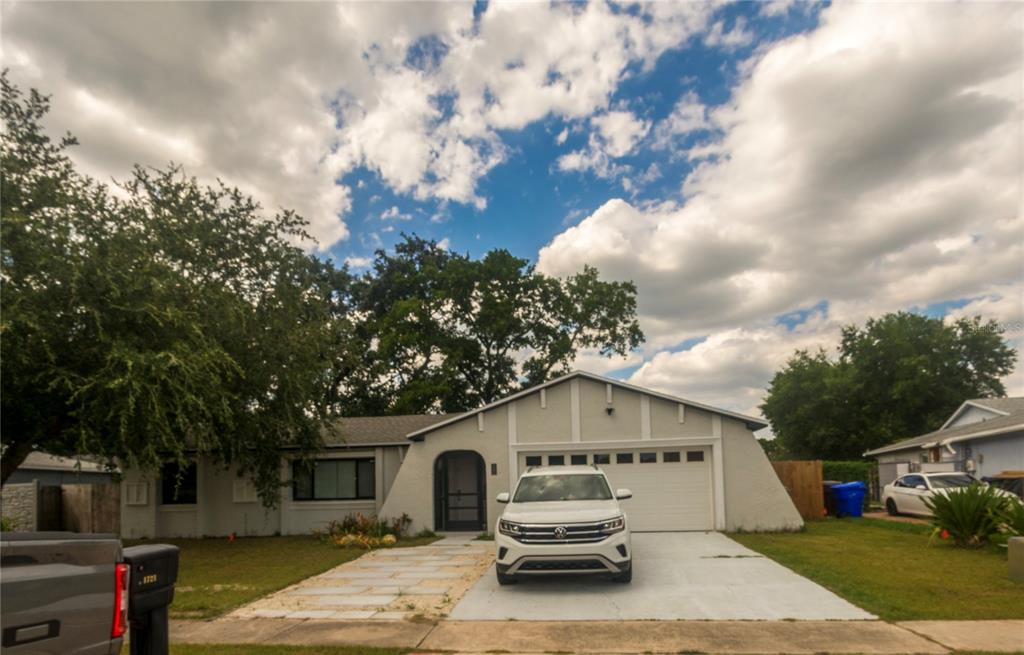 A single-story house with a white exterior, a garage, and a car parked in the driveway — 1721 FREEMAN DRIVE, KISSIMMEE, FL