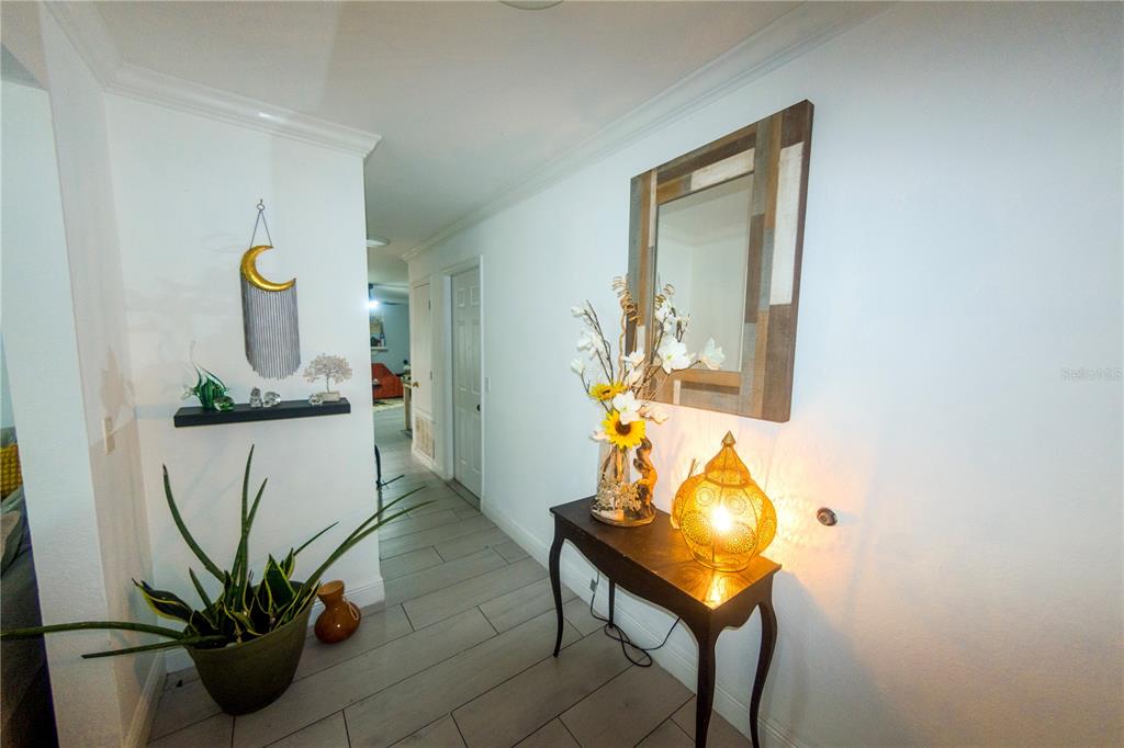 A hallway features a console table with a lamp, a mirror, and a potted plant — 1721 FREEMAN DRIVE, KISSIMMEE, FL
