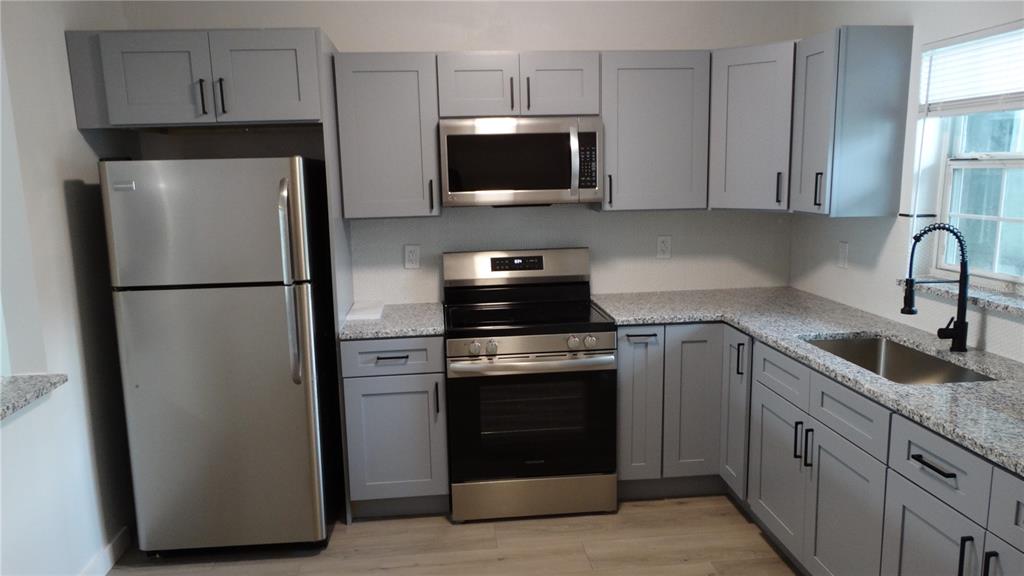 A kitchen featuring gray cabinets, stainless steel appliances, and speckled granite countertops — 14417 AMERICANA CIRCLE UNIT 204, TAMPA, FL