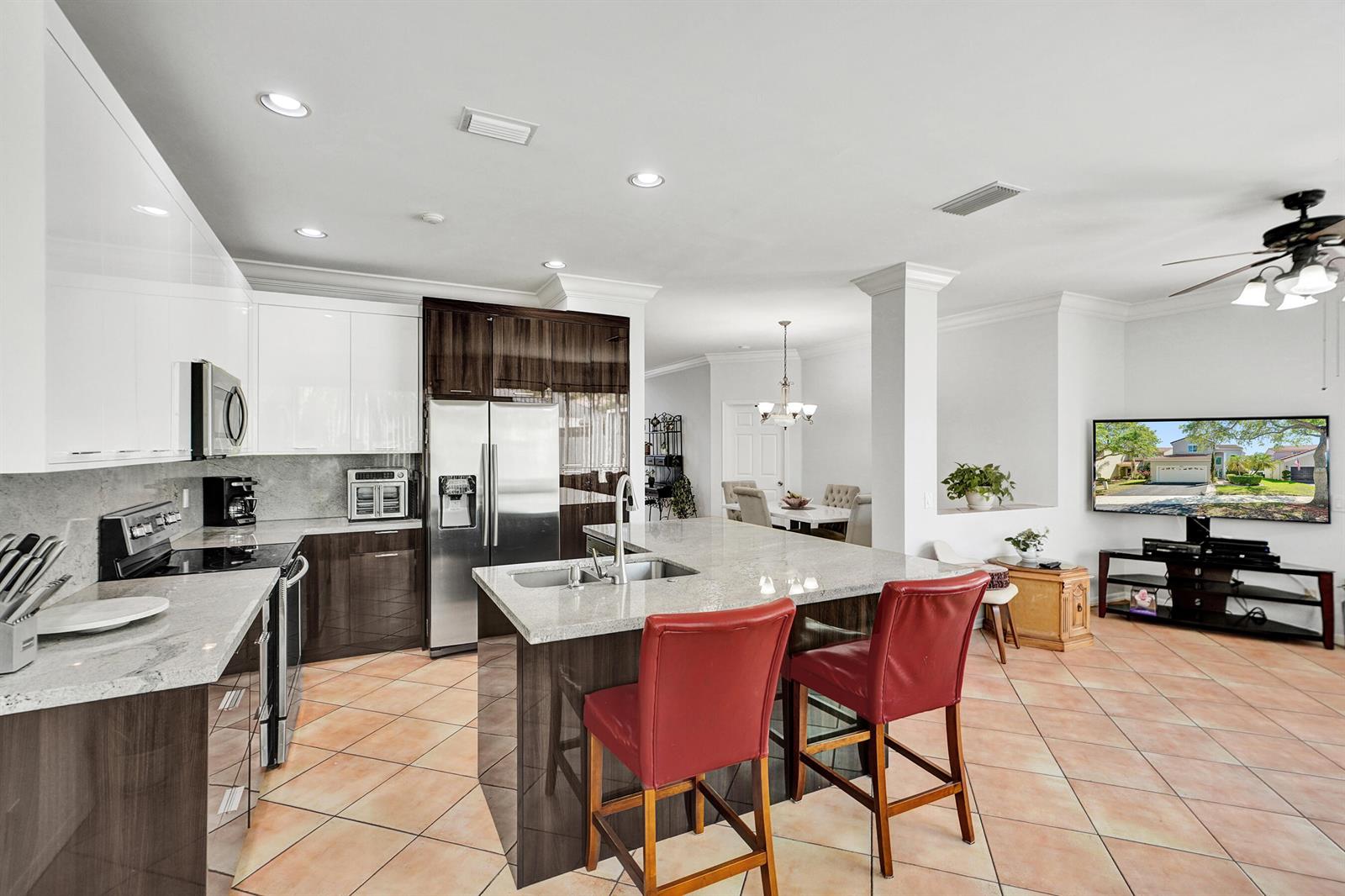 A kitchen features a granite-topped island, dark wood cabinetry, white upper cabinets, and tile flooring — 873 Stanton Drive, Weston FL 33326, WESTON, FL