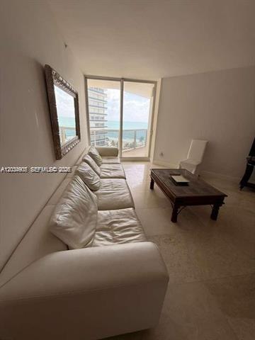 A living room features a white leather sofa, a wooden coffee table, and ocean views — 9595 Collins Ave # I, Surfside FL 33154, SURFSIDE, FL