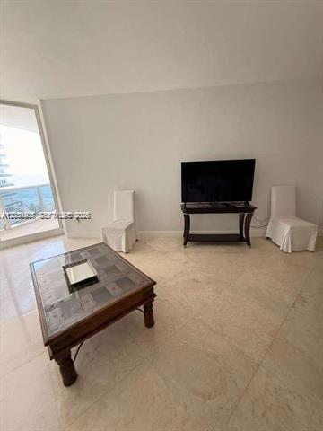 A living room features a glass-topped coffee table, a television on a stand, and chairs — 9595 Collins Ave # I, Surfside FL 33154, SURFSIDE, FL