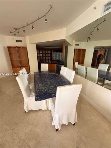 A dining room features a blue stone table, white slipcovered chairs, and a large wall mirror — 9595 Collins Ave # I, Surfside FL 33154, SURFSIDE, FL