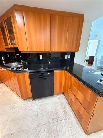 A kitchen features wood cabinets, black countertops, a stainless steel sink, and a black dishwasher — 9595 Collins Ave # I, Surfside FL 33154, SURFSIDE, FL