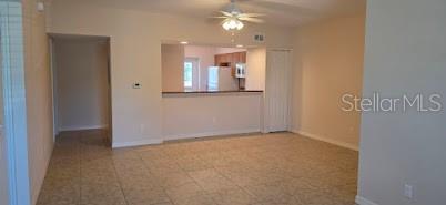 An open-concept living area features light-colored tile flooring and a kitchen pass-through window — 26172 EXPLORER ROAD UNIT 2, PUNTA GORDA, FL