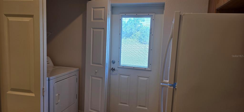 A laundry area features a white dryer, a door with a window, and a refrigerator — 26172 EXPLORER ROAD UNIT 2, PUNTA GORDA, FL