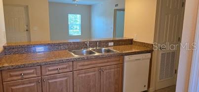 A kitchen features wood cabinets, granite countertops, a double sink, and a white dishwasher — 26172 EXPLORER ROAD UNIT 2, PUNTA GORDA, FL