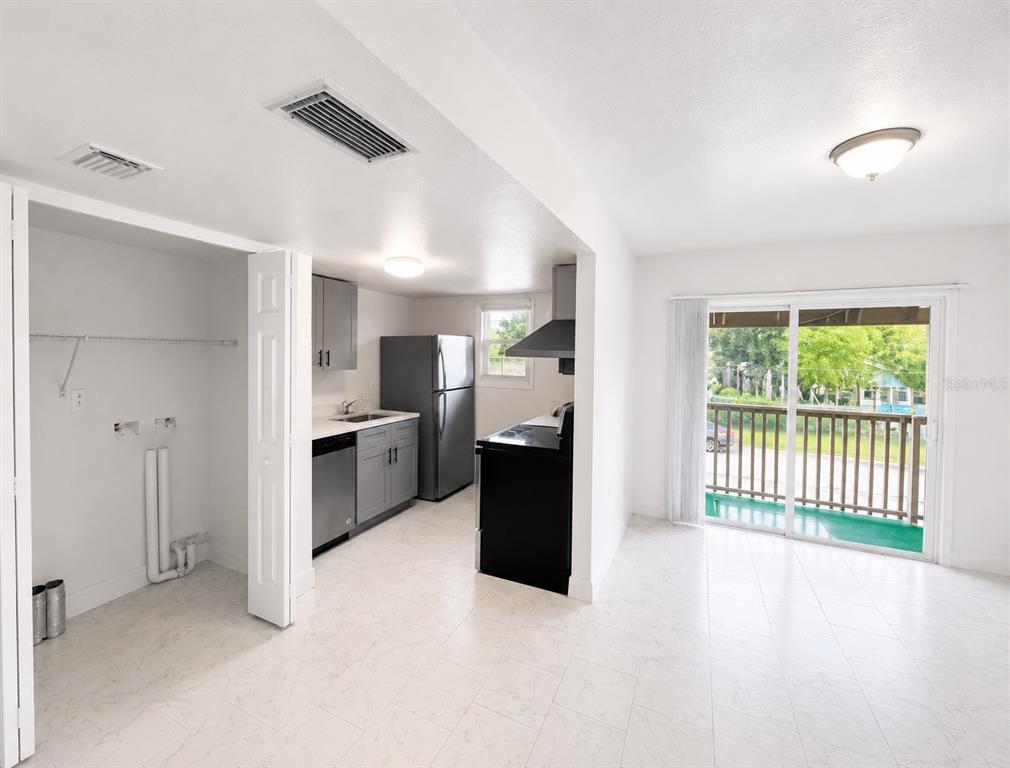 A kitchen with grey cabinets and black appliances opens to a room with a balcony — 2751 L B MCLEOD ROAD UNIT 2751, ORLANDO, FL