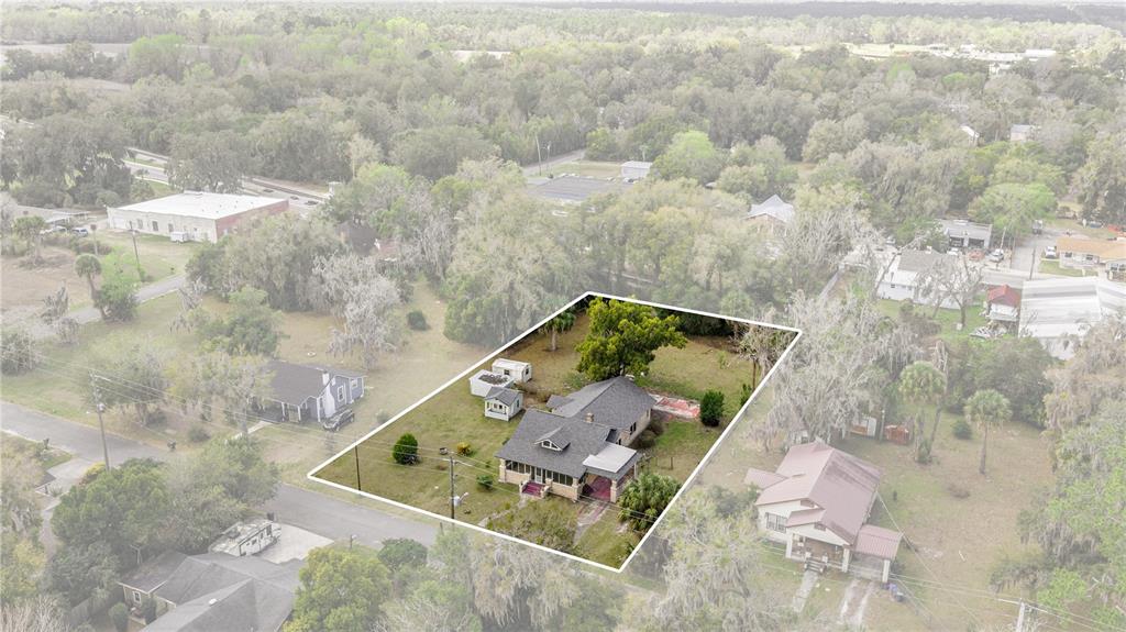 An aerial view shows a single-story house with a metal roof on a grassy lot — 7018 SE 222ND STREET, HAWTHORNE, FL
