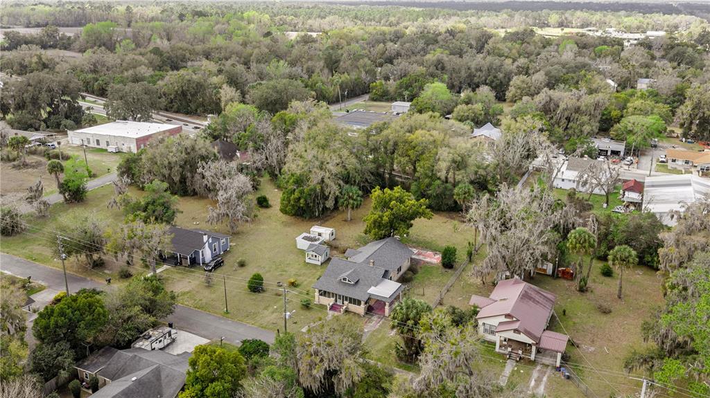 An aerial view shows several houses and outbuildings situated on a large, tree-filled lot — 7018 SE 222ND STREET, HAWTHORNE, FL