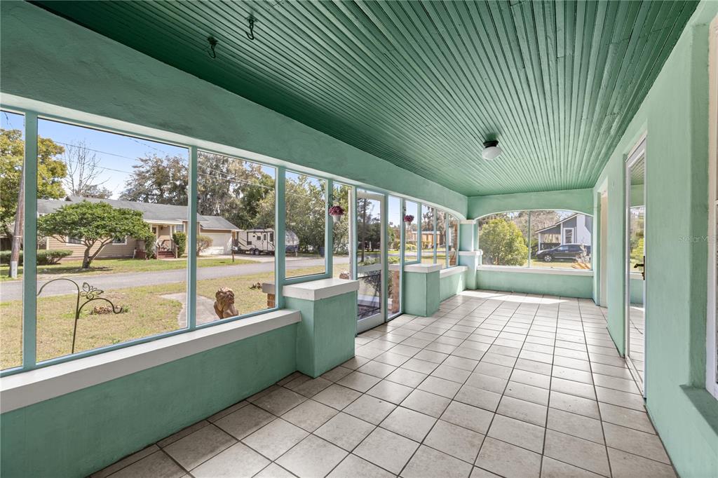 A sunroom with light green walls, a green beadboard ceiling, and white tiled flooring — 7018 SE 222ND STREET, HAWTHORNE, FL