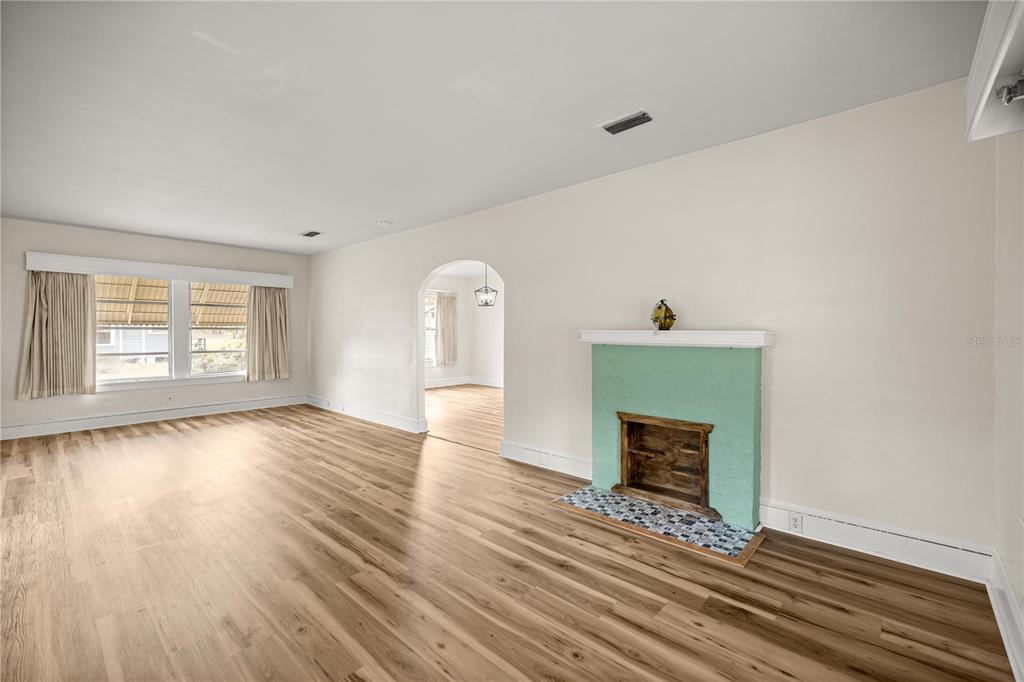 A living room features light wood-look flooring, a green brick fireplace, and an arched doorway — 7018 SE 222ND STREET, HAWTHORNE, FL