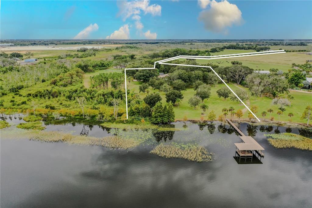 An aerial view shows a grassy property with trees and a dock on a lake — 8006 LAKE LOWERY ROAD, HAINES CITY, FL
