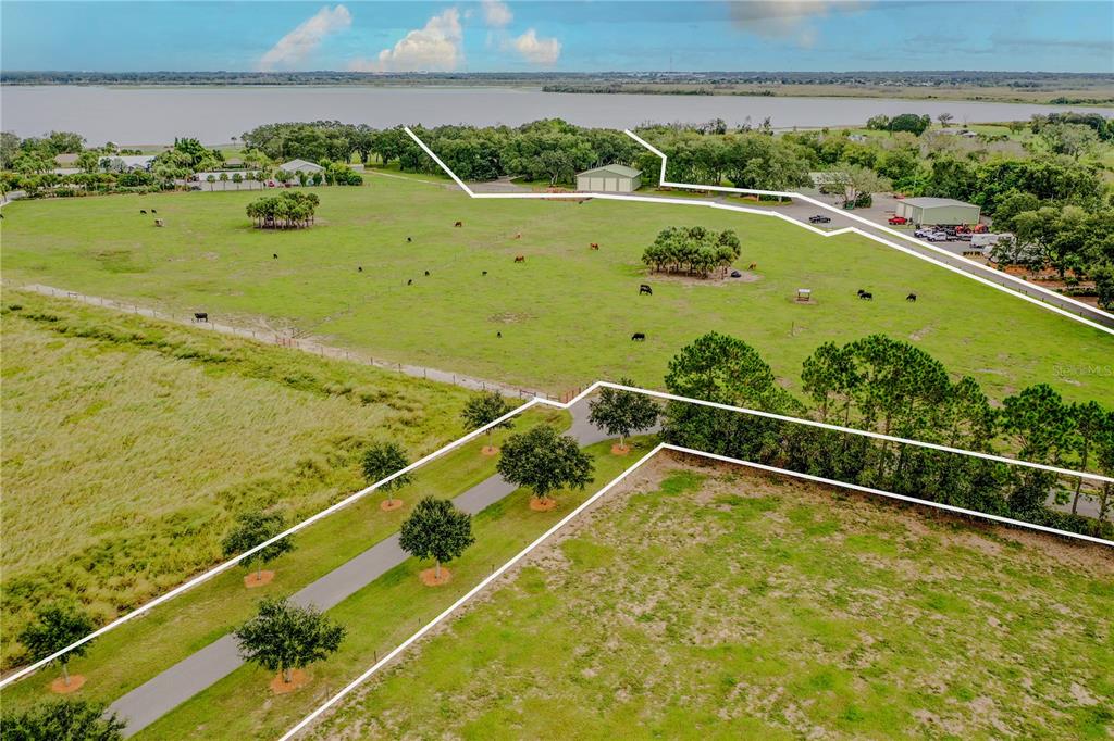 An aerial view shows a large, fenced pasture with trees, outbuildings, and a paved driveway — 8006 LAKE LOWERY ROAD, HAINES CITY, FL