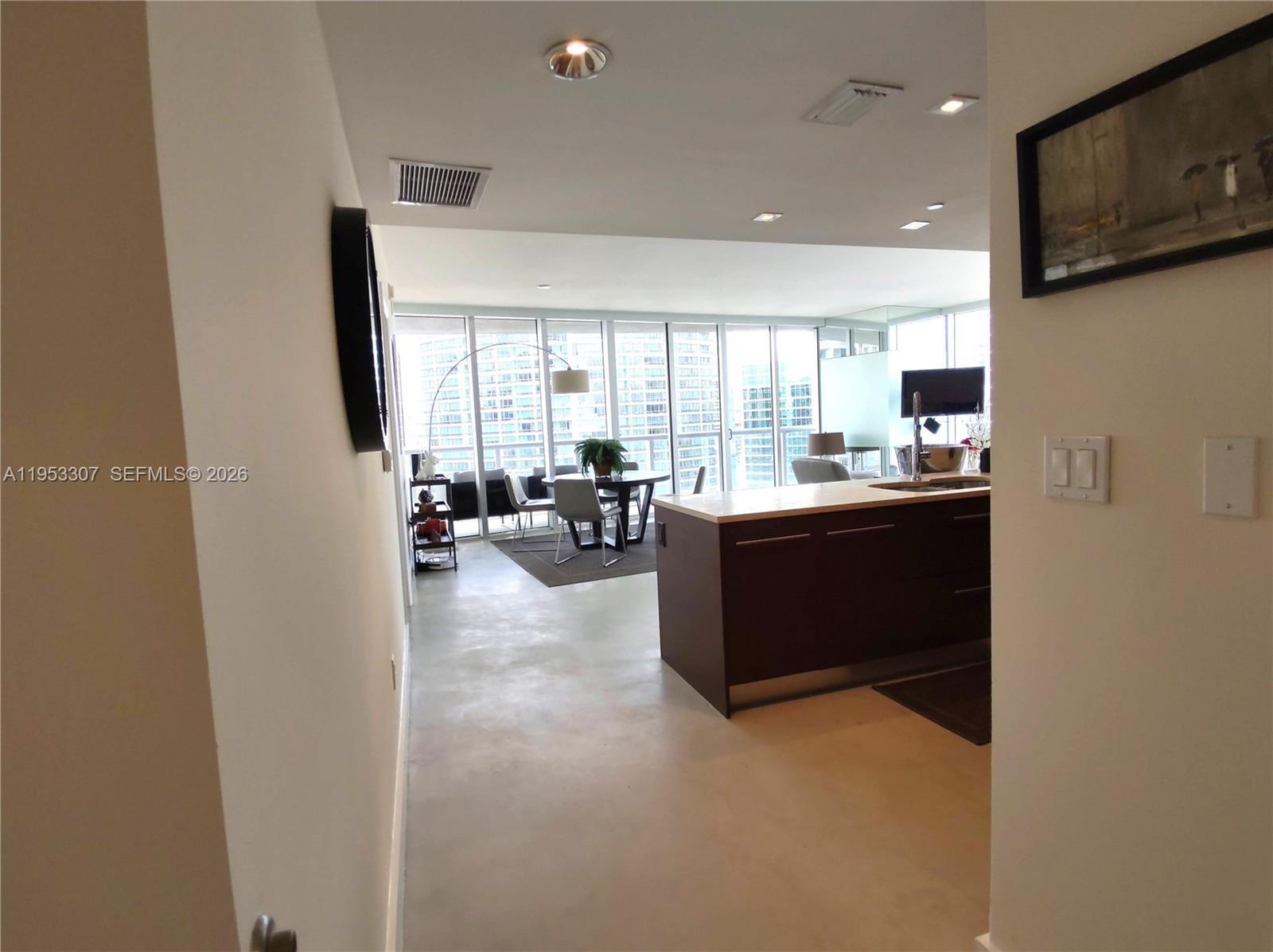 A view from a hallway into an open-concept kitchen and dining area with floor-to-ceiling windows — 465 Brickell Ave # 4402, Miami FL 33131, MIAMI, FL