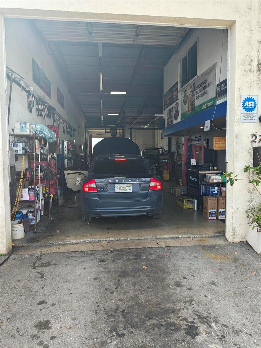 A dark Volvo is parked inside an automotive repair shop with tools and equipment — 2702 Rockey Drive, West Palm Beach FL 33409, WEST PALM BEACH, FL