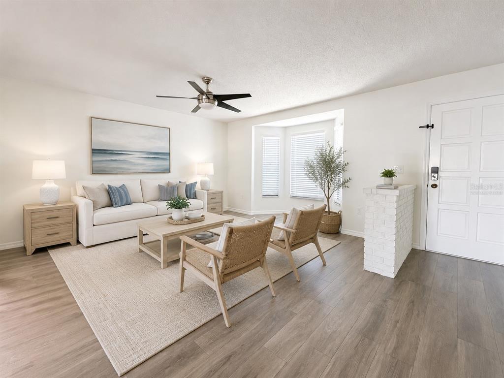 A living room with a white sofa, two woven chairs, and a white brick partition — 3209 PAFKO DRIVE, SARASOTA, FL
