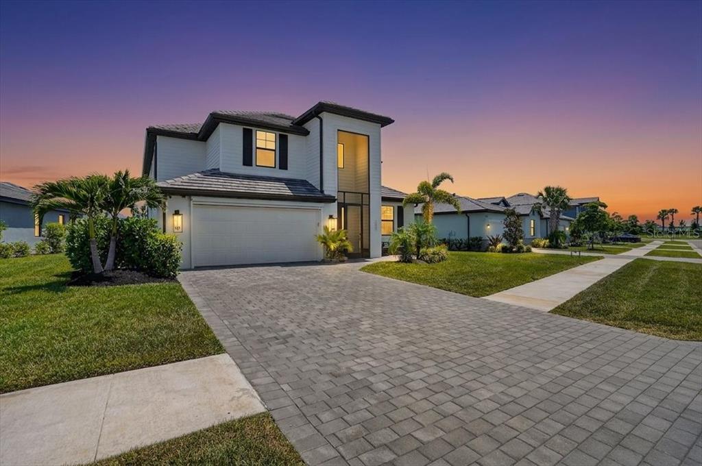 A two-story house with a white exterior, a paved driveway, and a sunset sky — 10865 SUN DROP STREET, VENICE, FL