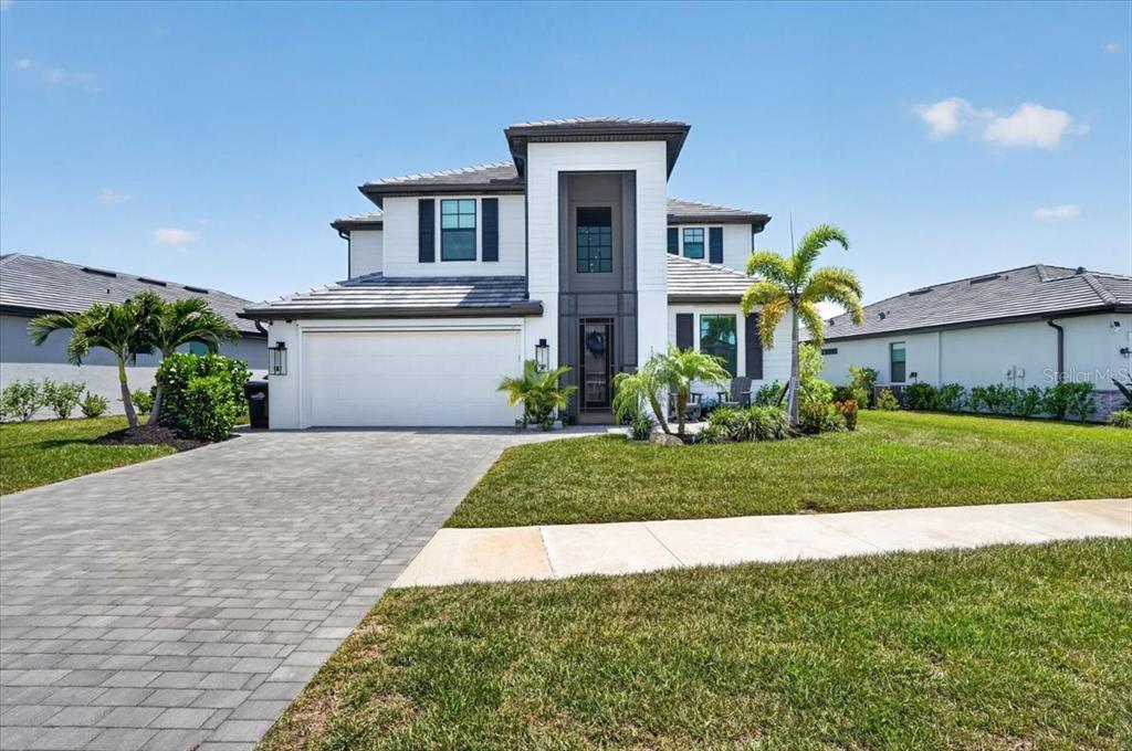 A two-story house with a white exterior, dark trim, and a paved driveway — 10865 SUN DROP STREET, VENICE, FL