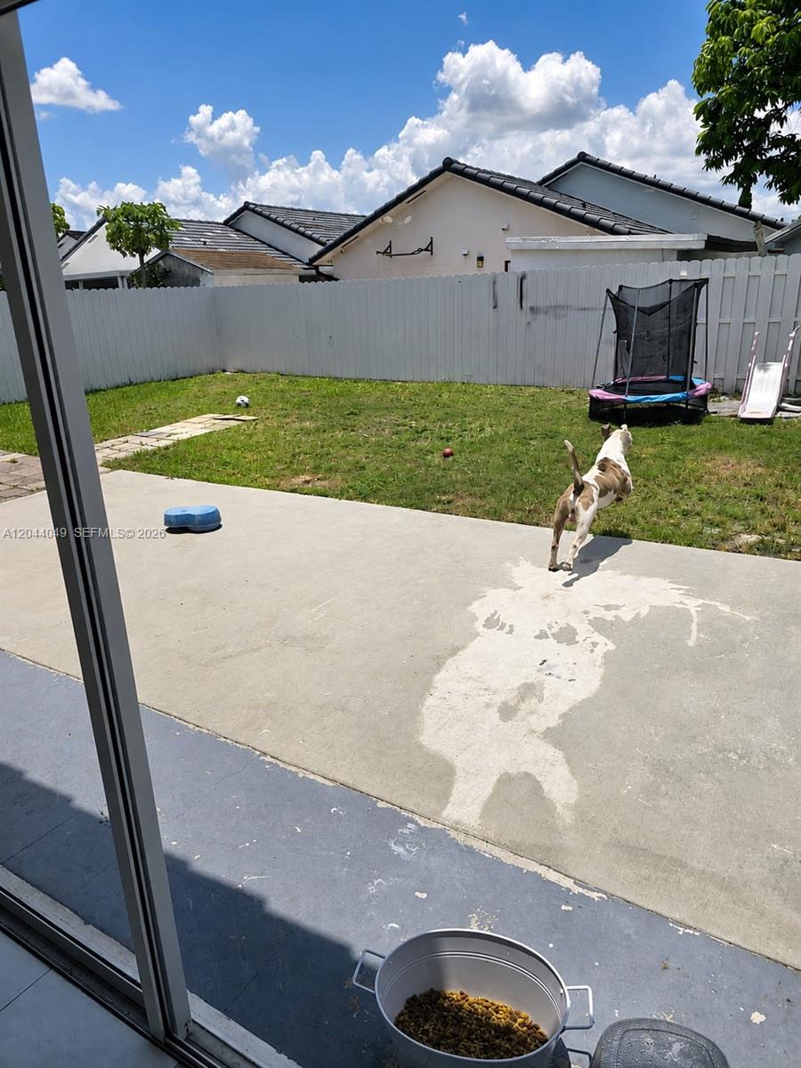 A dog jumps across a concrete patio in a fenced backyard with a small trampoline — 17834 SW 144th Ct # 0, Miami FL 33177, MIAMI, FL
