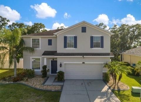 A two-story house with a beige exterior, blue shutters, and a two-car garage — 2623 HOLLY BLUFF COURT, PLANT CITY, FL
