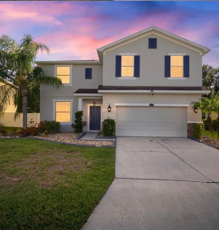 A two-story suburban house with a beige exterior, blue shutters, and a two-car garage — 2623 HOLLY BLUFF COURT, PLANT CITY, FL
