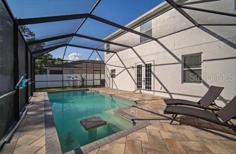 A screened-in swimming pool with a paver deck and two lounge chairs — 2623 HOLLY BLUFF COURT, PLANT CITY, FL