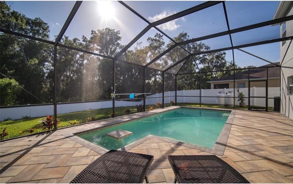 A screened-in swimming pool with a paver patio and a white vinyl fence in back — 2623 HOLLY BLUFF COURT, PLANT CITY, FL