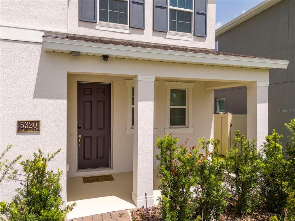 The exterior of a two-story house features a covered front porch with a dark door — 5320 LAKE VIRGINIA STREET, WINTER GARDEN, FL