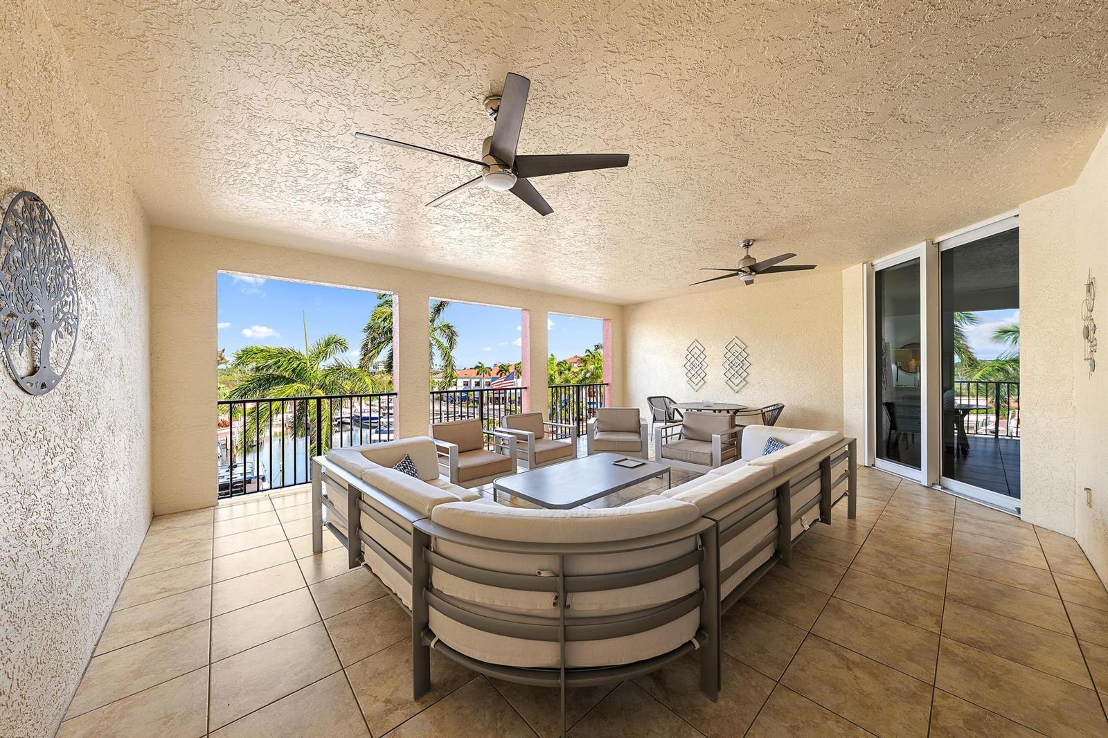 A covered outdoor patio features a large sectional sofa, ceiling fans, and a water view — 400 S Us Hwy 1 # 303, Jupiter FL 33477, JUPITER, FL