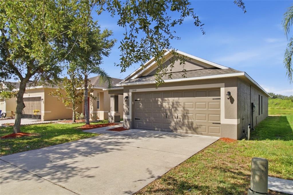 A beige single-story house with a two-car garage and a concrete driveway — 15519 TELFORD SPRING DRIVE, SUN CITY CENTER, FL