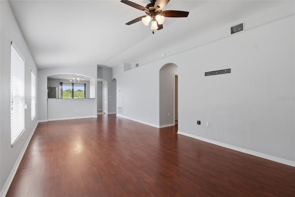 A spacious living room features light gray walls, dark wood flooring, and a ceiling fan — 15519 TELFORD SPRING DRIVE, SUN CITY CENTER, FL
