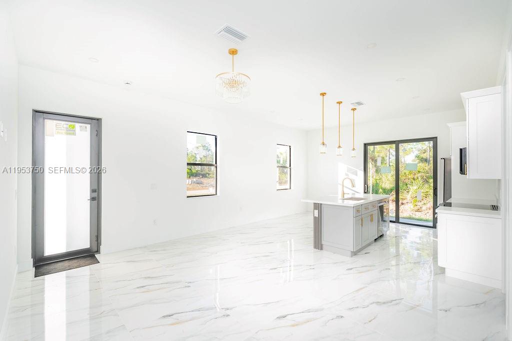 A bright kitchen and living area features white marble floors, a gray island, and glass doors — 1005 Brenton Ave, Lehigh Acres FL 33974, LEHIGH ACRES, FL