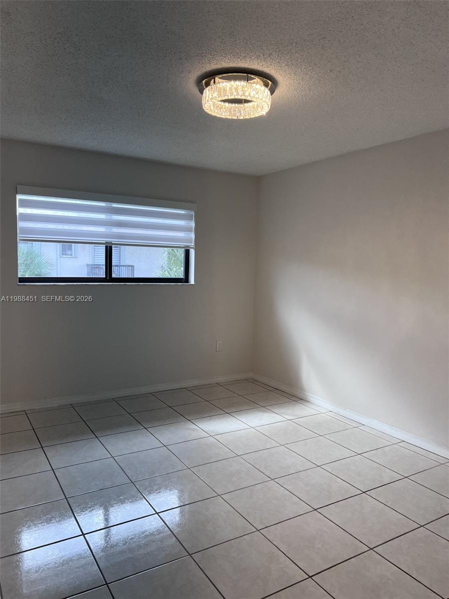 An empty room features white tile flooring, a window with blinds, and a circular light fixture — 5480 W 21st Ct # 404, Hialeah FL 33016, HIALEAH, FL