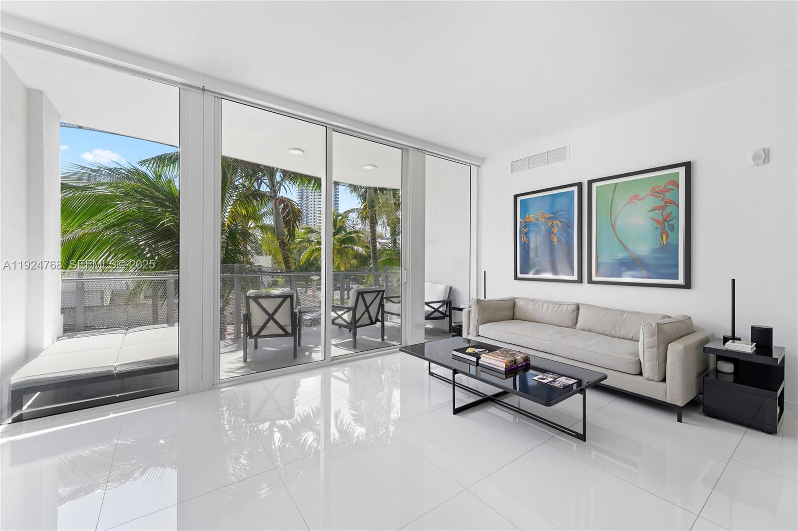 A modern living room features white tile floors, a beige sofa, and floor-to-ceiling glass doors — 2100 Park Ave # 201, Miami Beach FL 33139, MIAMI BEACH, FL