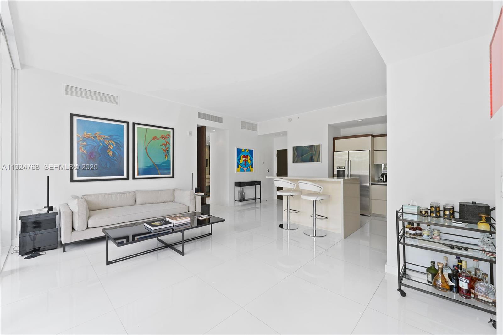 A modern living room features white tile floors, a sofa, a coffee table, and a kitchen — 2100 Park Ave # 201, Miami Beach FL 33139, MIAMI BEACH, FL