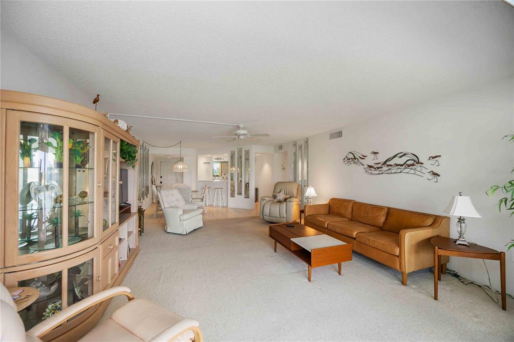 A living room with beige carpet, a tan leather sofa, and a large wooden display cabinet — 5050 MARIANNE KEY ROAD UNIT 1B, PUNTA GORDA, FL